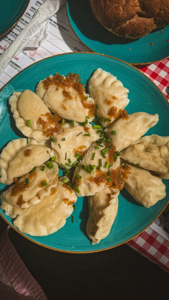 Top view of delicious dumplings garnished with herbs and fried onions, served on a vibrant blue plate.