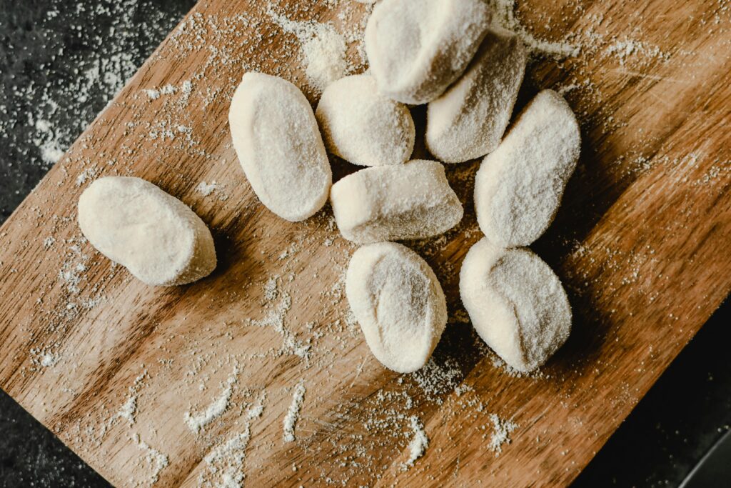 Raw dumplings arranged on a wooden chopping board, dusted with flour.